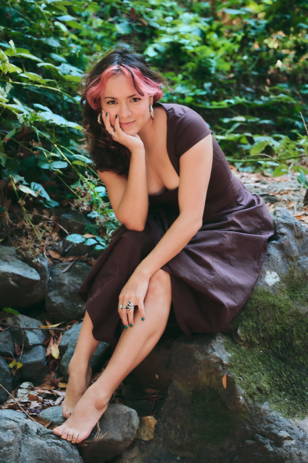 Lunarosa Peralta seated among greenery, hand resting at her cheek